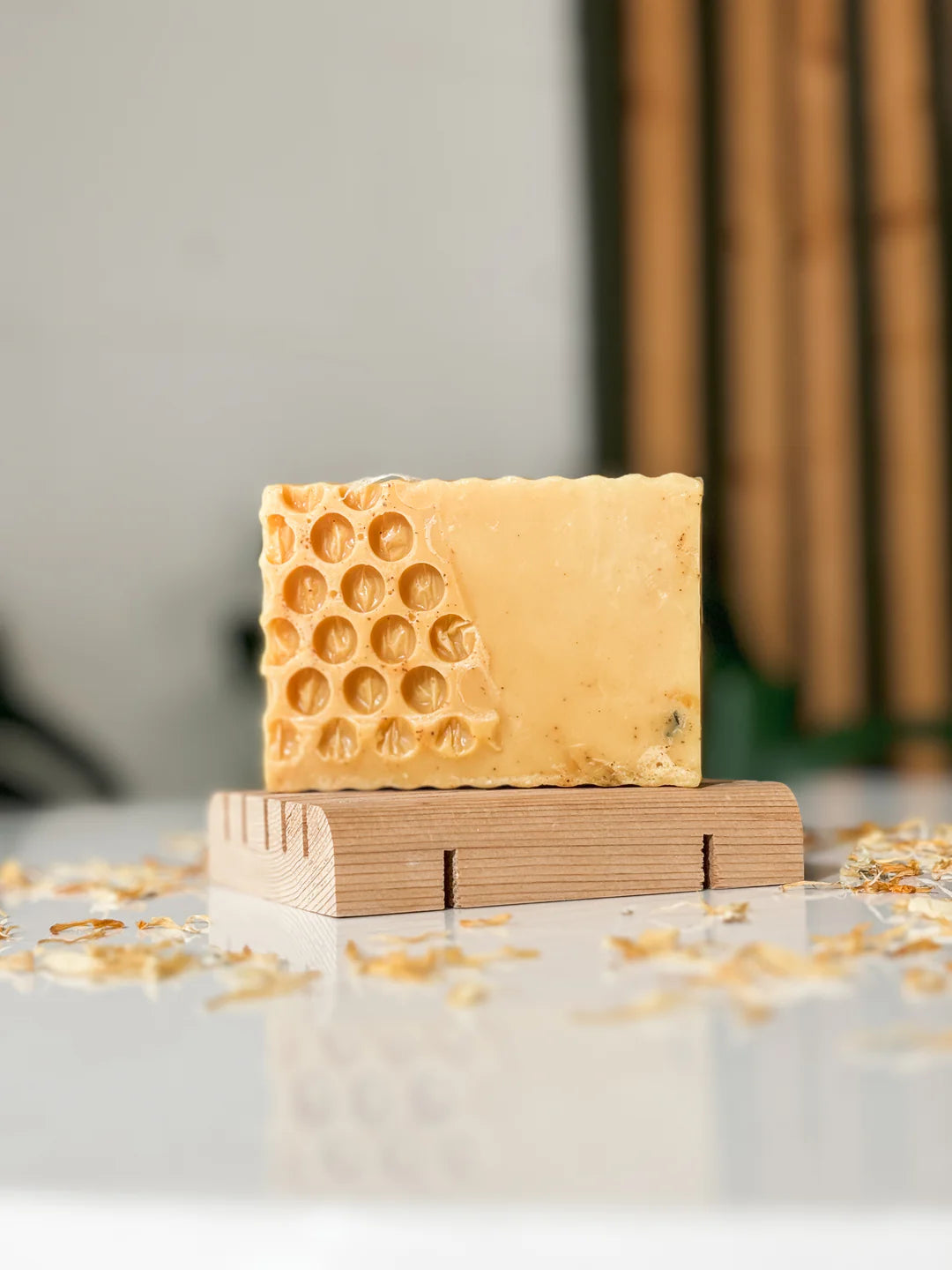 Bar of soap with honeycomb pattern on a wooden block against a neutral background