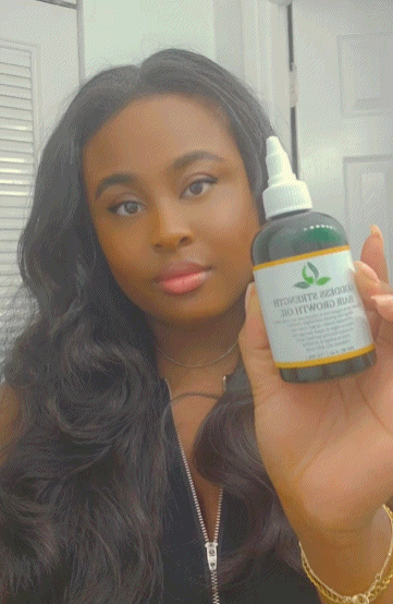 Goddess Strength Hair Growth Oil bottle held by a woman with long, healthy hair.