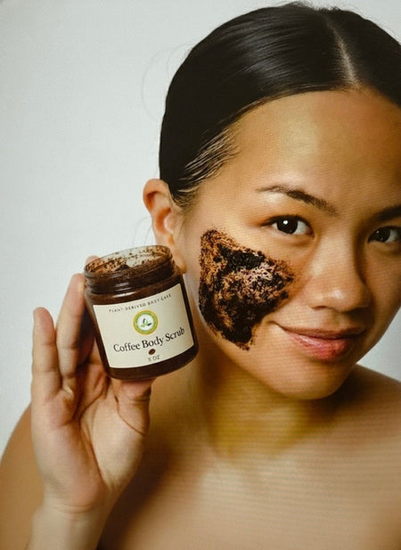 woman applying coffee scrub on face holding jar of coffee body scrub exfoliating skin
