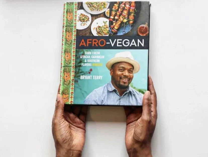 Afro-Vegan cookbook featuring farm-fresh African, Caribbean, and Southern flavors by Bryant Terry, held in hands.