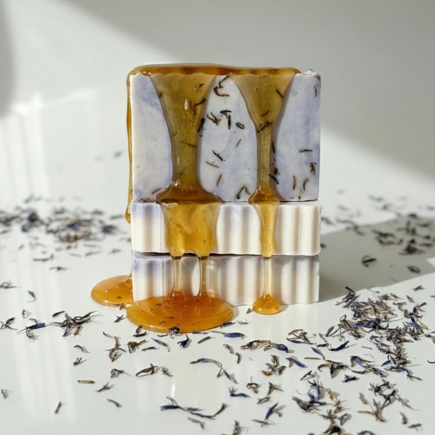 Bar of soap with gold and white marbled pattern on a surface with dried flowers.