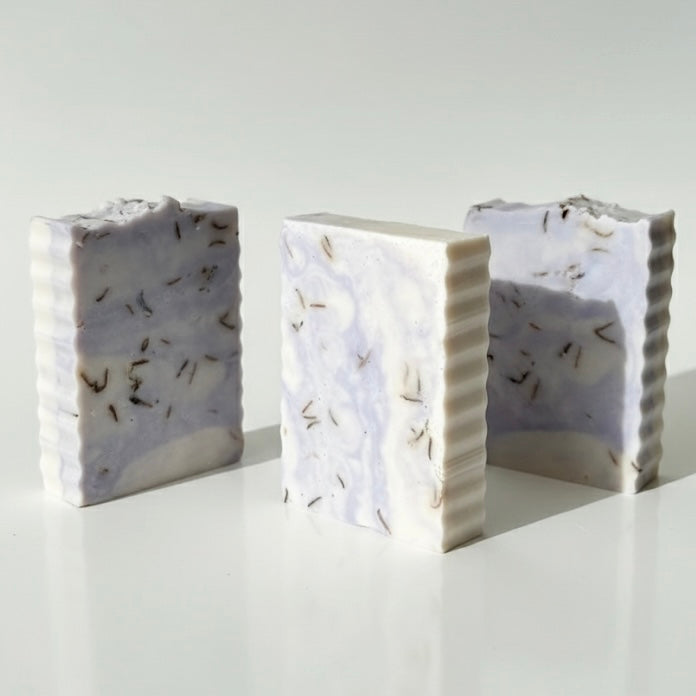 Three rectangular soap bars with textured surfaces on a white background
