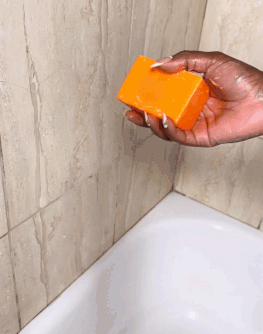 Passion Fruit Soap held above bathtub, enhances skin luminosity and radiance.