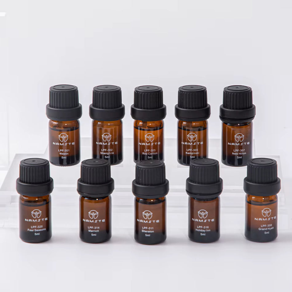 Namste essential oil set of 10 amber glass bottles with black caps, 5ml each, arranged on clear risers