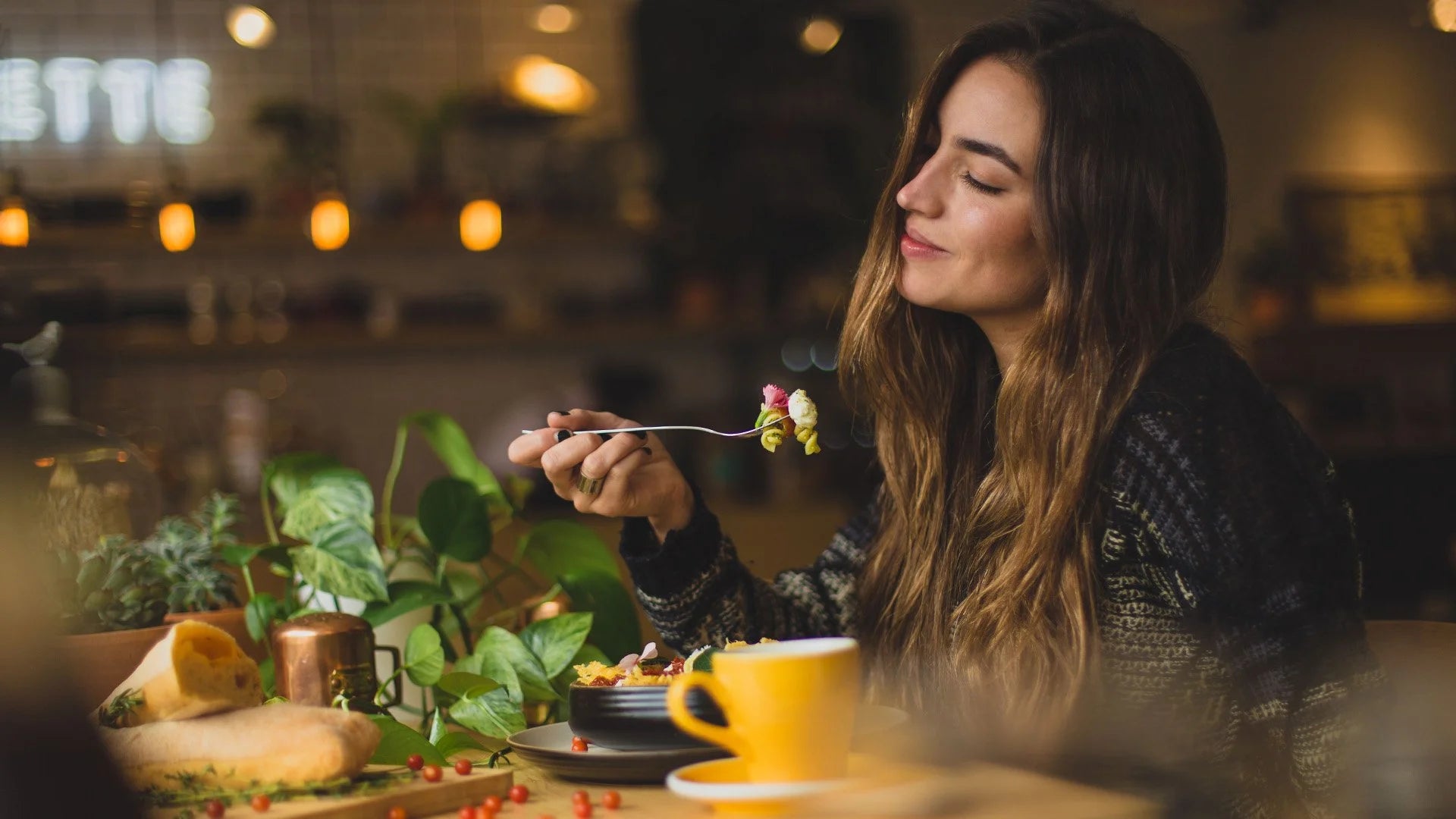 Load video: Woman eating at a restaurant with a warm and cozy atmosphere