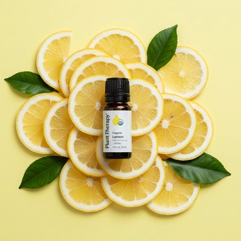 Essential oil bottle surrounded by lemon slices on a yellow background